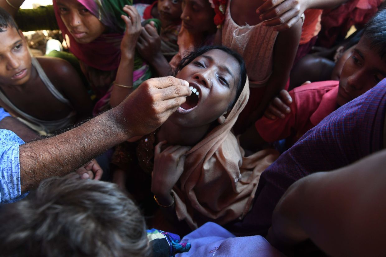 A Rohingya refugee receives an oral cholera vaccine from a Bangladeshi volunteer at the Thankhali refugee camp in Ukhia district on October 10, 2017. – Photo: INDRANIL MUKHERJEE/AFP